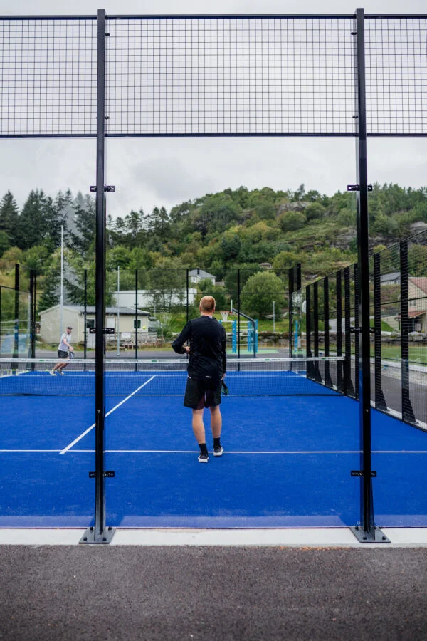 To menn som spiller utendørs padeltennis
