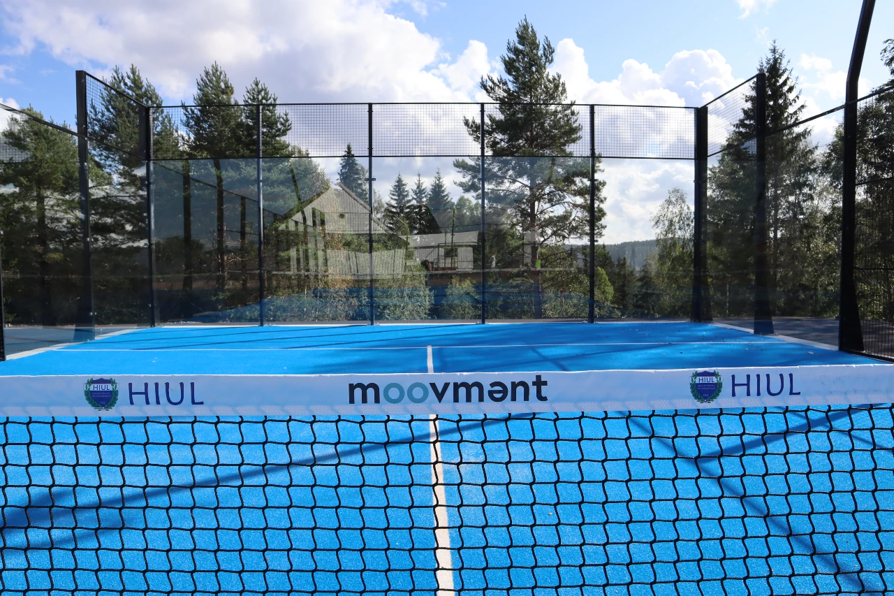 Padeltennisbane med blått kunstgress i naturskjønne omgivelser